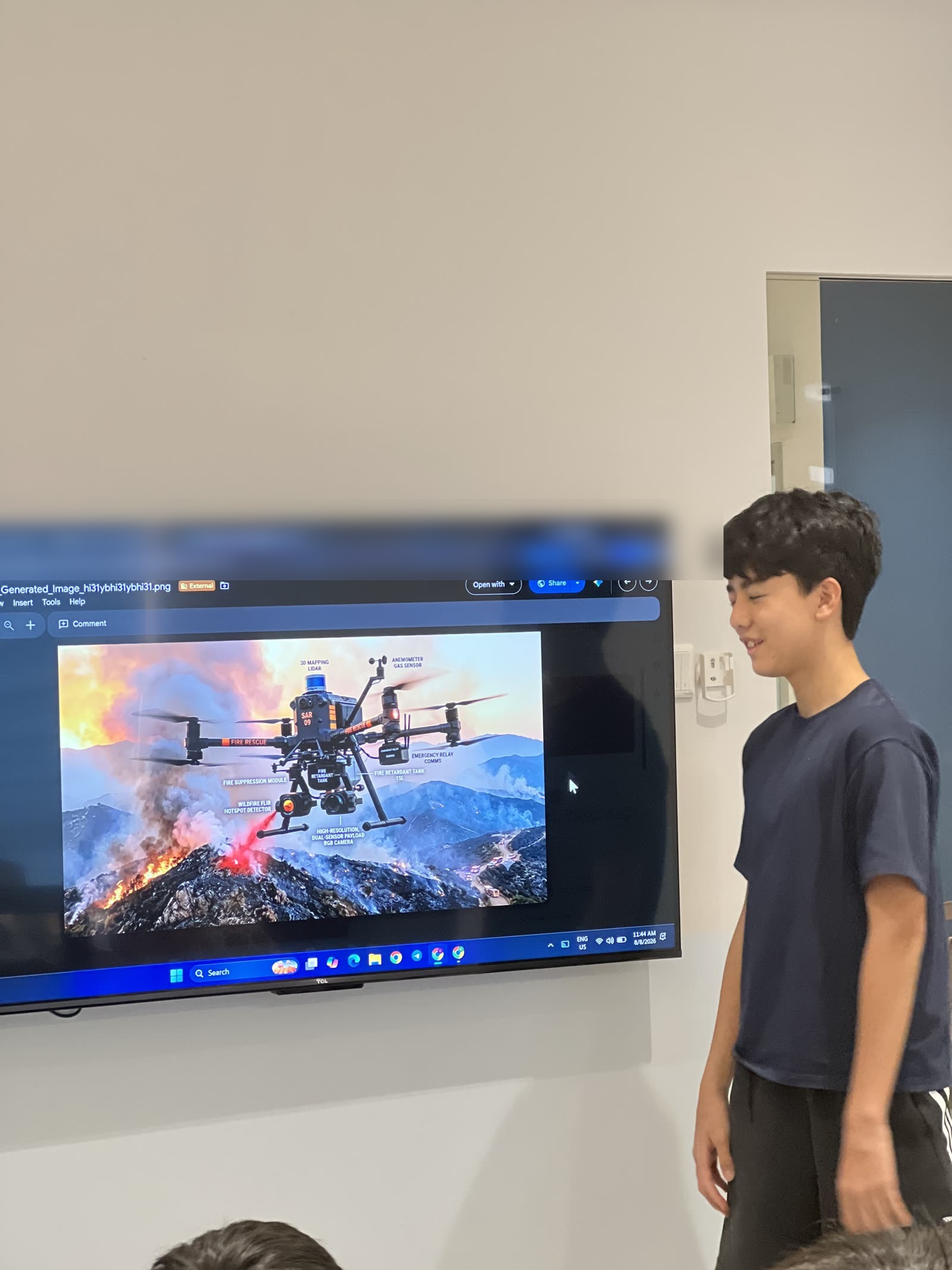 Sebastien standing beside a screen showing his drone over a burning hillside