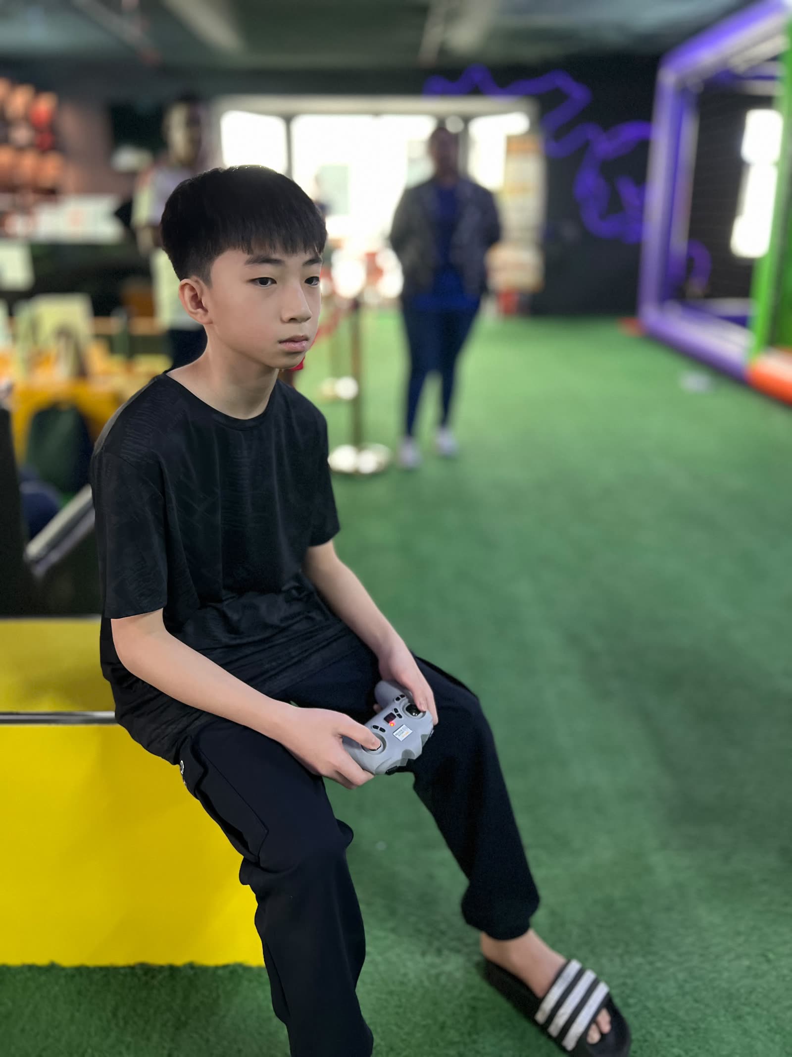 Zhi Lee sitting at the arena with a drone controller in his hands